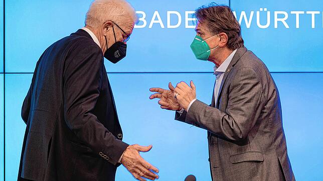 Manfred Lucha und Ministerpräsident Winfried Kretschmann unterhalten sich nach einer Pressekonferenz im Dezember 2021.