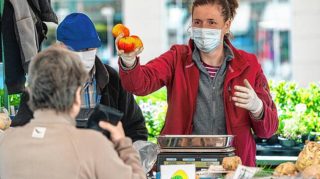 Die Verkäuferin eines Gemüsestandes in Straubing spricht mit Schutzmaske zu einer Kundin. Straubing gehört zu den Corona-Hotspots im ...
