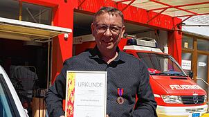 Andreas Brodbeck mit Urkunde und Medaille im Depot der Betriebsfeuerwehr der Varo im Binninger Hafen.