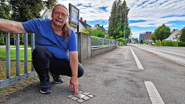 Thomas Kliebenschedel deutet auf den bislang einzigen Stolperstein in Friedrichshafen. Er befindet sich an der Zeppelinstraße in Fischbach.