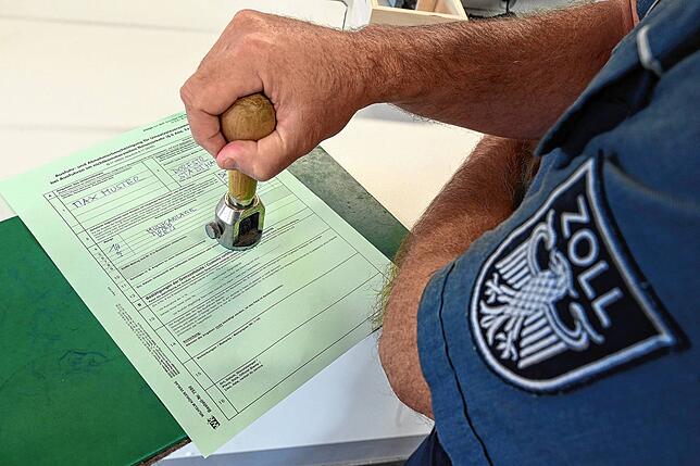 Ein Zöllner stempelt in einer Zoll-Abfertigungstelle einen Ausfuhrschein ab.