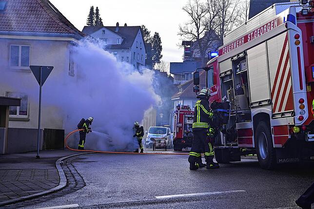 Mit einem Wasserstrahl wird das Feuer gelöscht. Dampf steigt auf.