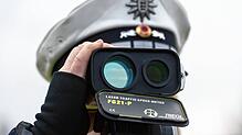 Ein Polizist kontrolliert mit einem Lasermessgerät die Geschwindigkeit der Fahrzeuge.