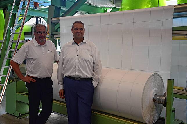 Geschäftsführer Uwe Zimmermann und der Betriebsratsvorsitzende Christian Schellbach von den Global Safety Textiles vor einer Geweberolle ...