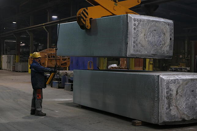 Ein Mitarbeiter platziert einen Aluminium-Walzbarren, wie das Stockacher Aluminiumwerk sie aus Schrott gewinnt.