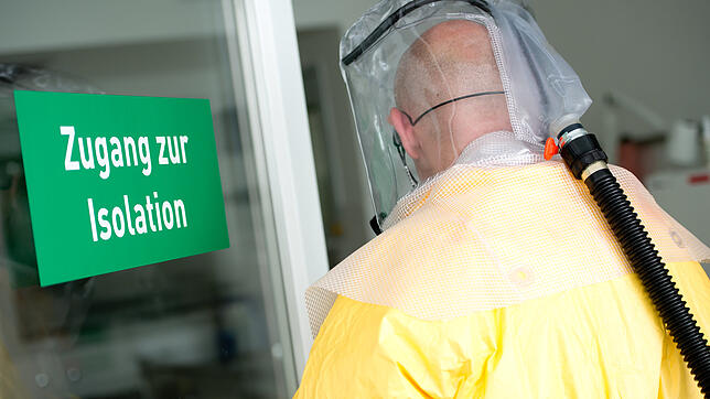 Ein Mann in Schutzausrüstung betritt bei einem Pressetermin eine Sonderisolierstation in einem Münchner Klinikum. In Deutschland ist ...