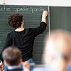Eine Lehrerin schreibt in einer Schule Worte an eine Tafel. Der Lehrermangel im Land ist so akut, dass Schulen zum Teil zur ...