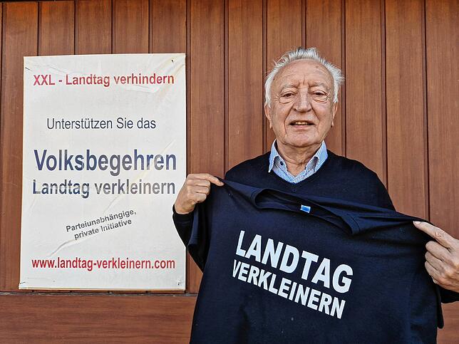 Dieter Distler, 81 vor der Garage am Haus mit dem Plakat „Landtag verkleinern“.