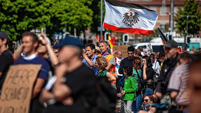 Die Reichsflagge, Erkennungssymbol der rechten Szene, weht über einer Gruppe von Demonstranten bei einer Querdenken-Demonstration in ...