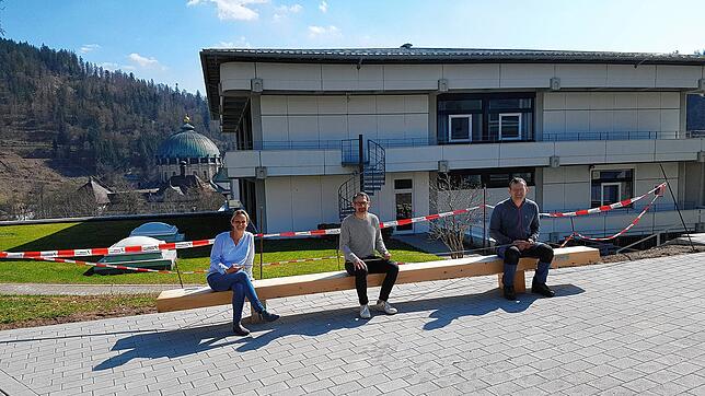 Schulleiterin Susanne Schwer, Architekt Edgar Thoma und Hausmeister Michael Iorillo haben auf einer der neuen Bänke Platz genommen.