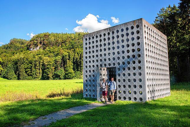 SÜDKURIER-Mitarbeiter Katja Huber und Yannick Peter vor einem durchlöcherten Kubus mitten auf einer grünen Wiese. Das Wasserhaus St. ...
