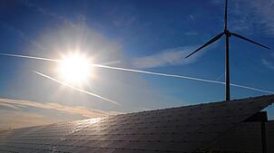 Ein Windrad steht hinter den Solarzellen einer Solarkraftanlage im Sonnenschein. Bis zu zwölf Windenergieanlagen können nach den ...