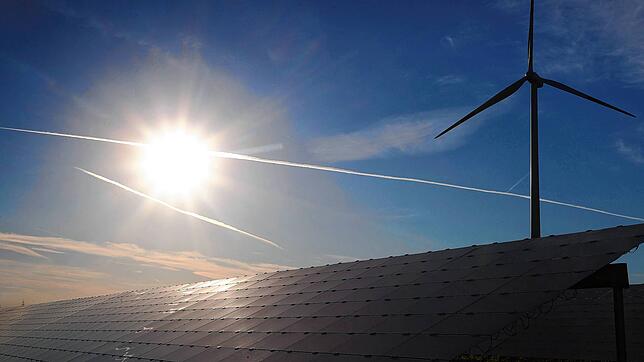 Ein Windrad steht hinter den Solarzellen einer Solarkraftanlage im Sonnenschein. Bis zu zwölf Windenergieanlagen können nach den ...