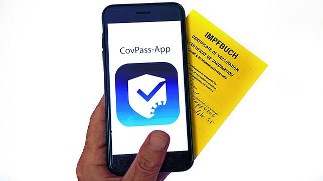 Das Logo der CovPass-App ist neben einem Impfbuch auf einem Smartphone zu sehen. Der digitale Corona-Impfpass in Deutschland soll an ...