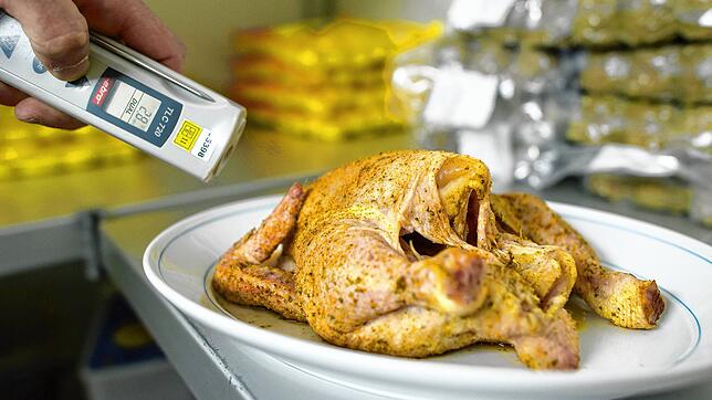 Ein Lebensmittelkontrolleur überprüft bei einer Betriebskontrolle die Temperatur eines Hähnchens. Hier ein Symbolbild.