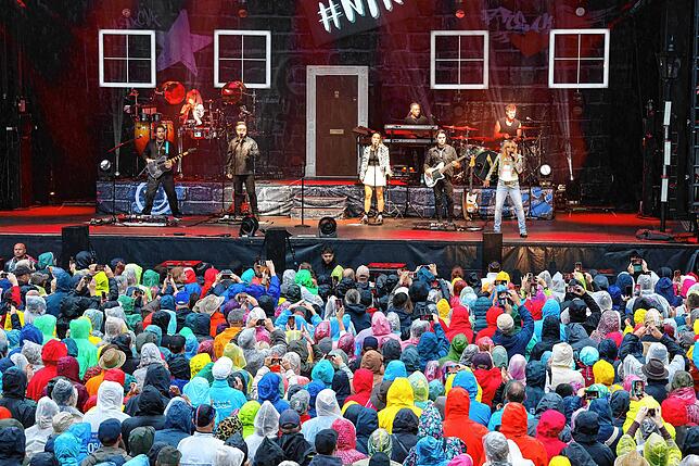 Vor der Bühne auf dem Rathausplatz tummeln sich über 4000 Besucher in Regenausrüstung.