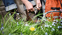 ARCHIV - 29.04.2015, Nordrhein-Westfalen, Köln: ILLUSTRATION - Eine Wandererin schnürt ihre Wanderschuhe. Viele Menschen scheint es in ...