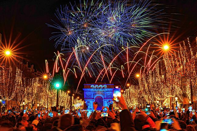 Auf den Champs Élysées in Paris begrüßen die Menschen mit Blick auf den Arc de Triomph das Jahr 2023.