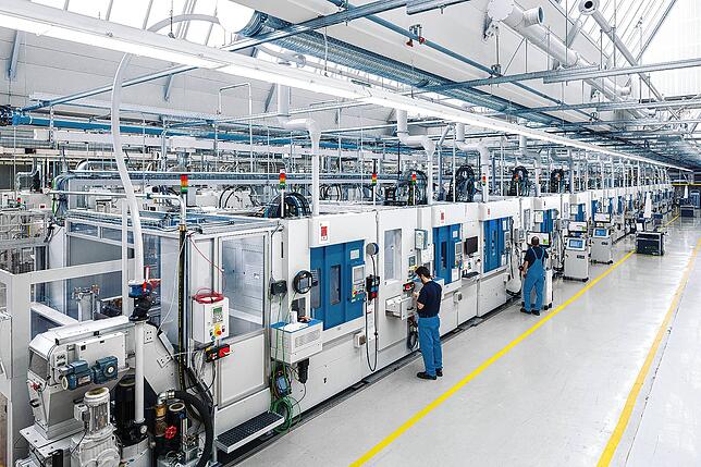 Mitarbeiter vor der voll automatisierten Fertigungslinie für Pkw-Stahlkolben im Werk in Rottweil.