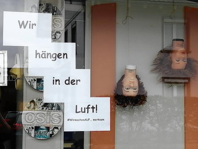 Die Frisierpuppen hängen kopfüber: „Wir machen auf...merksam“, steht am Schaufenster von Barbara Martin.