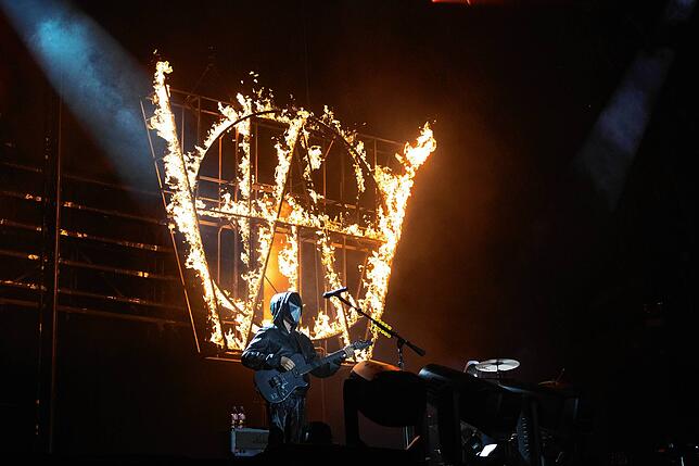 Vor Alan Walker steht die britische Band Muse auf der Bühne. Die Maske fällt in den nächsten Minuten, die Feuereffekte bleiben eindrücklich.