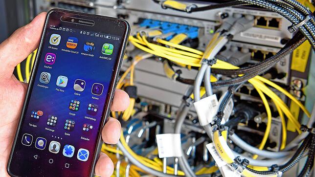 Ein Techniker hält ein Smartphone in einer Mobilfunkstation. Ein defektes Bauteil in einer solchen Station störte das Handynetz in ...