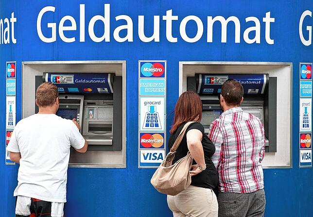 Kunden stehen an Bankautomaten, um sich mit Bargeld einzudecken (Symbolbild).