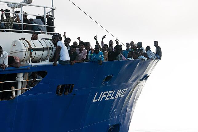 Menschen winken vom Schiff der Seenotretter von Lifeline. Einige der großen Schiffe wurden inzwischen an die Kette gelegt, damit sind ...
