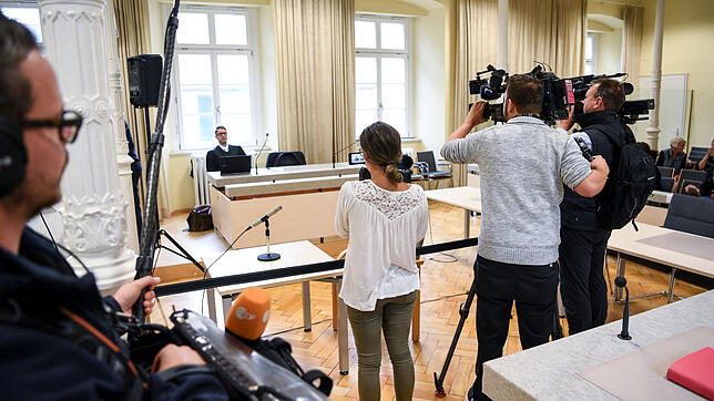 Verteidiger Manuel Reiger sitzt hinter der Anklagebank, während Pressevertreter ihn filmen. Rund ein Jahr nach einem Erpressungsfall mit ...