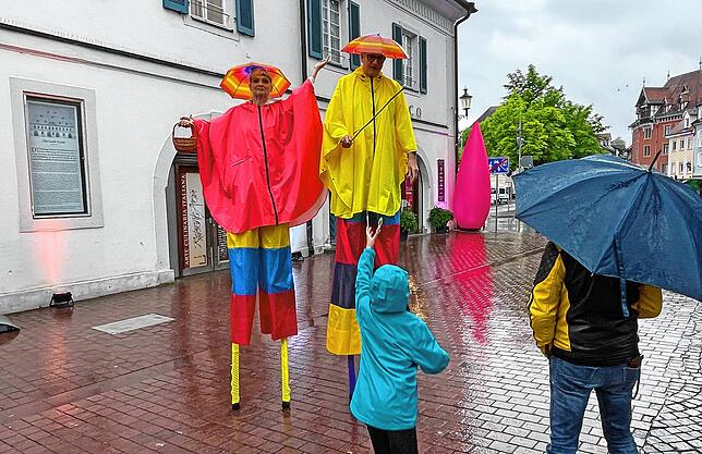 Unter Schirmhüten ließen sich die Stelzenläufer den Spaß nicht verregnen.