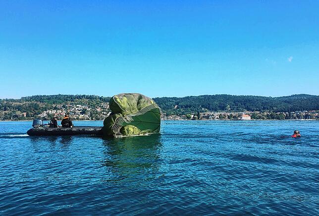 Ein Boot bei einem gelandeten Fallschirmspringer, der dann aus dem Wasser geholt wird.