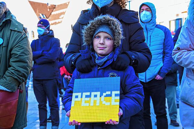 „Peace“, das englische Wort für Frieden, hat dieser Junge mit weißer Schrift auf seinen gelbblauen Untergrund aus ...