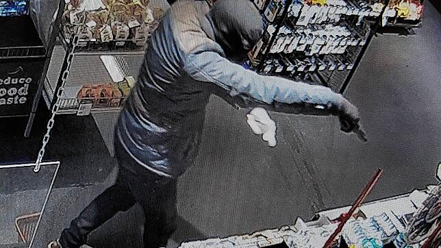 Der Täter während des Überfalls, aufgenommen von einer Überwachungskamera. Danach ergriff der Unbekannte die Flucht.