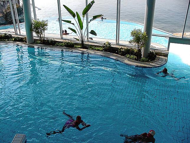 Die ersten Schwimmer begeben sich vom Innen- ins Außenbecken der Therme.