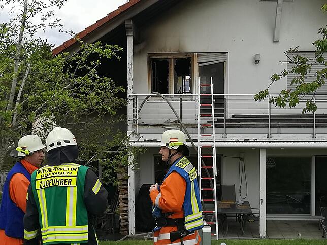 Die von der Dorfstraße abgewandte Seite des Brandhauses. An dem Holzstapel, der zwischen dem Zugführer und einem weiteren Feuerwehrmann ...