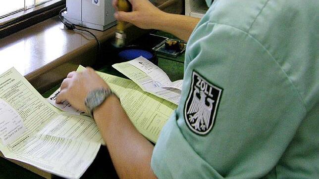 Ein Zollbeamter stempelt grüne Ausfuhrzettel ab.