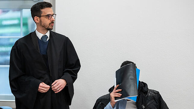 Ein Mann, der wegen Vergewaltigung und Freiheitsberaubung an seiner Schwester angeklagt ist, verdeckt sein Gesicht – hier im ersten ...