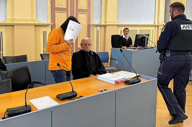 Der Angeklagte (l) betritt den Gerichtssaal und setzt sich neben seinen Verteidiger Georg Menz.