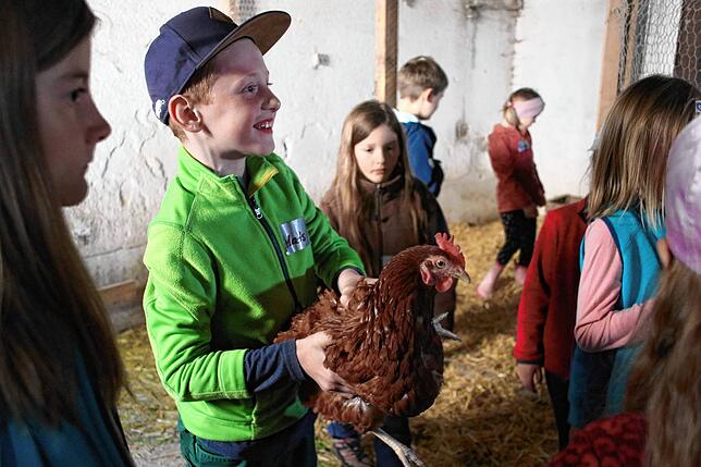 Strahlend hält Mats ein Huhn, wie er es zuvor von Martina Büche gelernt hatte.