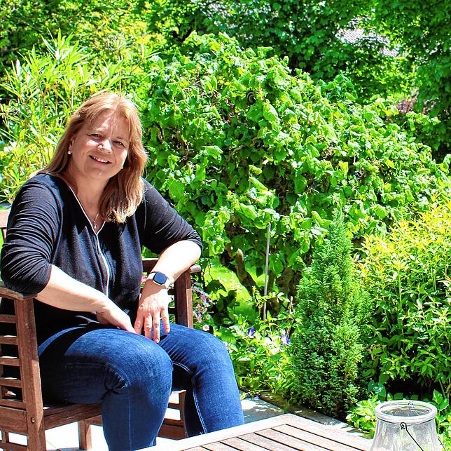 Britta Sauer-Böhm auf ihrer Terrasse: Zur Straße hin Gewerbegebiet, hinten raus ein halber Wald.