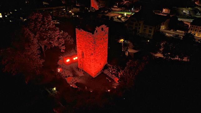 Der rot angestrahlte Bergfried der Schlossruine im Schweizer Laufenburg.