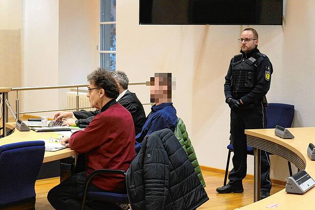 Der 39-jährige Angeklagte sitzt zwischen seinem Verteidiger und einem Dolmetscher für Russisch.