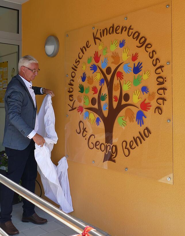 Bauplaner Bernhard Streit enthüllt das neue Logo der Kindertagesstätte St. Georg.