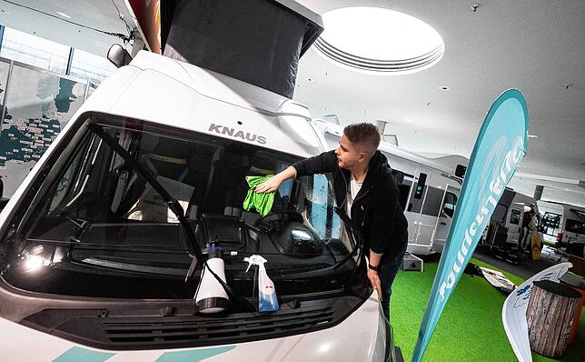 Alles muss glänzen: Ein Mann putzt die Windschutzscheibe eines Camper-Vans.