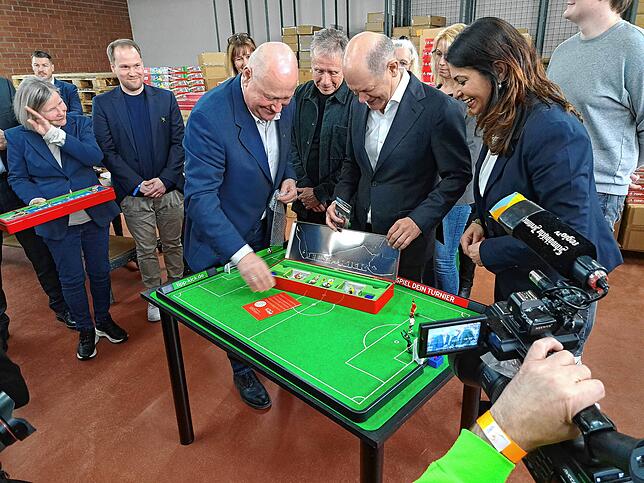 Mathias Mieg (links) überreicht dem Kanzler eine Retro-Edition des Spiels. Auch Derya Türk-Nachbaur (rechts) bekommt eine.