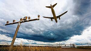 Dunkle Wolken ziehen über einen Airbus A320 hinweg, der am Stuttgarter Flughafen landet.