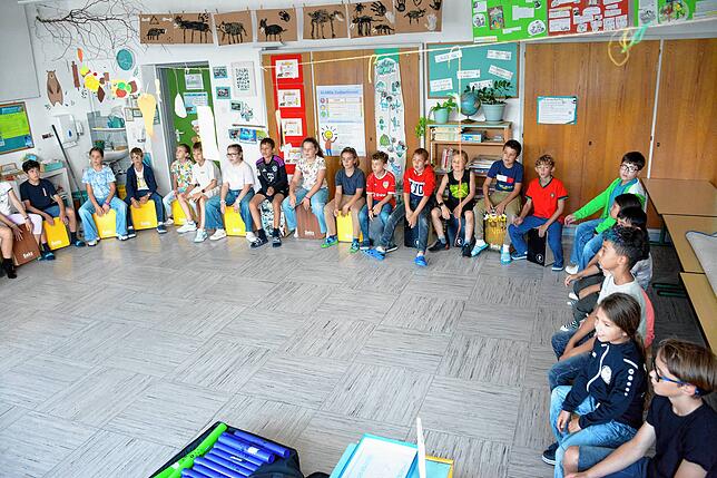 Erst zuhören, dann nachmachen: Die Kinder warten in der großen Runde auf ihren Einsatz.