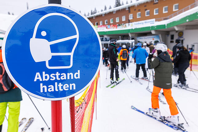 Skifahren am Feldberg Ein Schild mit der Aufschrift "Abstand halten" hängt nahe der Talstation der Feldbergbahn an einem Pfosten, während dahinter ...
