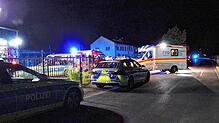 Polizei und Rettungsdienste stehen nach dem Messerangriff an der Asylbewerberunterkunft.