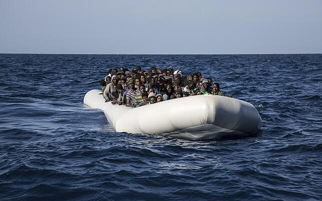 Flüchtlinge aus Afrika, darunter auch viele Gambier, sitzen in einem Schlauchboot, nachdem sie im Mittelmeer aufgespürt und aus Seenot ...